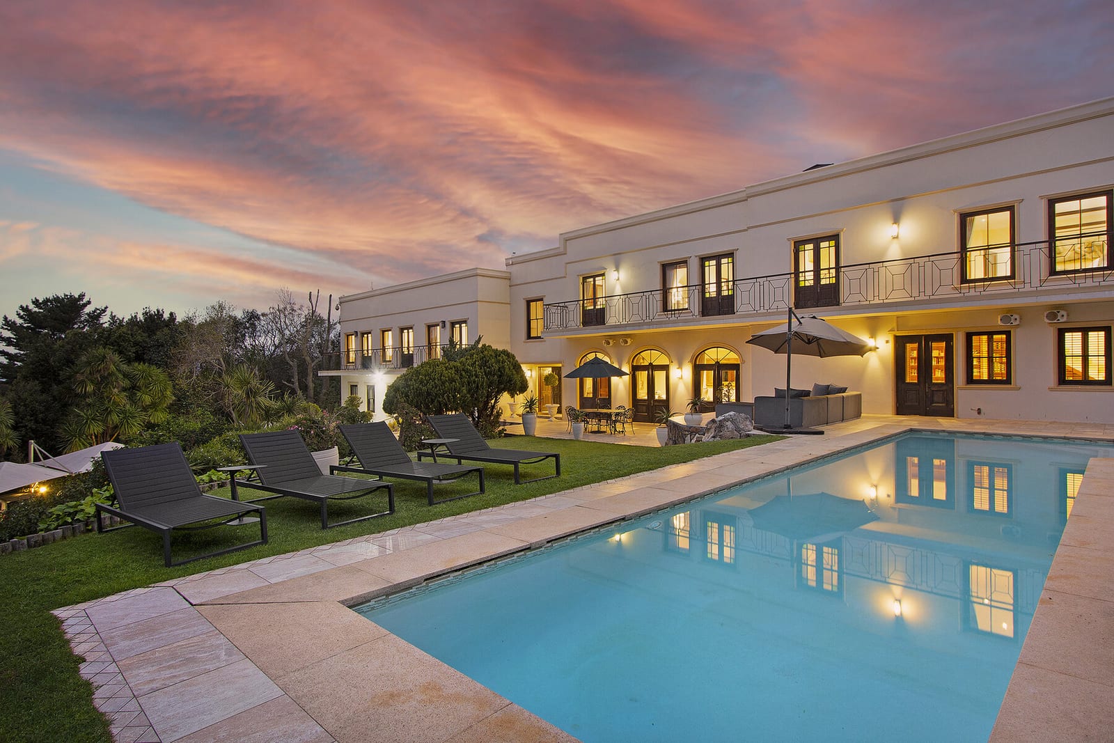 Lyonesse House and its illuminated swimming pool beneath the evening sky